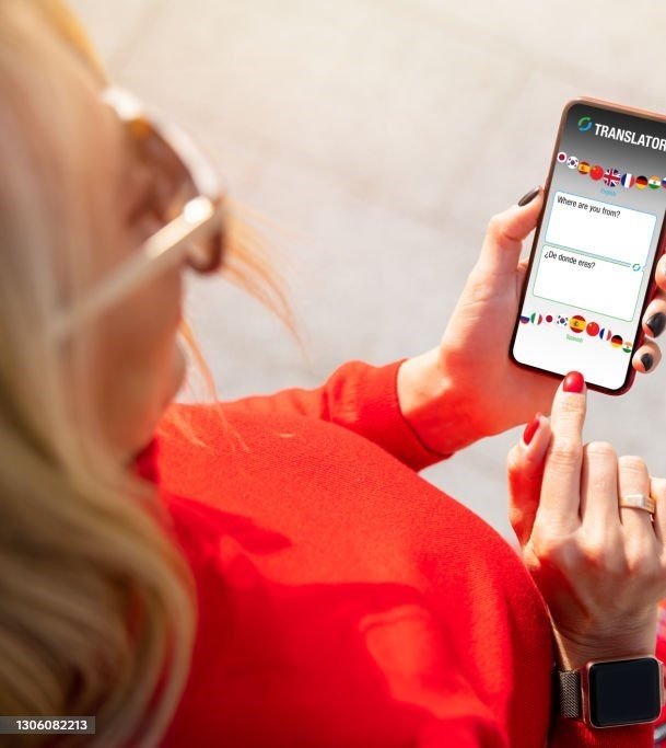  Woman using language translate app on mobile phone. Top view